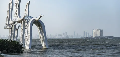 Mond-Bucht des Dushu-Sees in der Stadt Suzhou mit der Skyline im Hintergrund und einer Kranich-Großplastik im Vordergrund