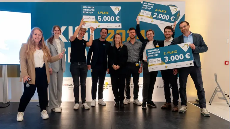 Gewinner stehen auf Bühne mit Scheck in der Hand