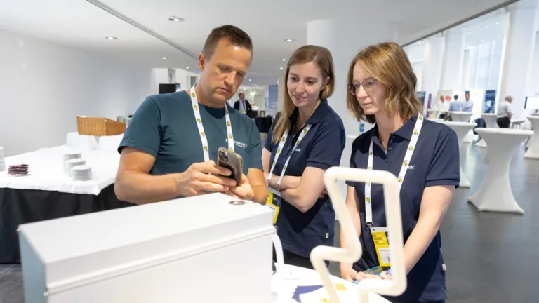 Austeller schauen gemeinsam in ein Smartphone