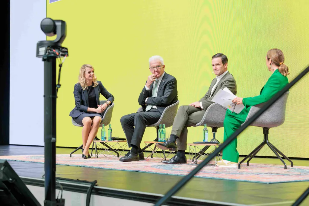 Im Bild ist die Bühne des Kongress BW 2024 mit vier Personen. Darunter die Moderatorin, zwei Unternehmer und Ministerpräsident Winfried Kretschmann.