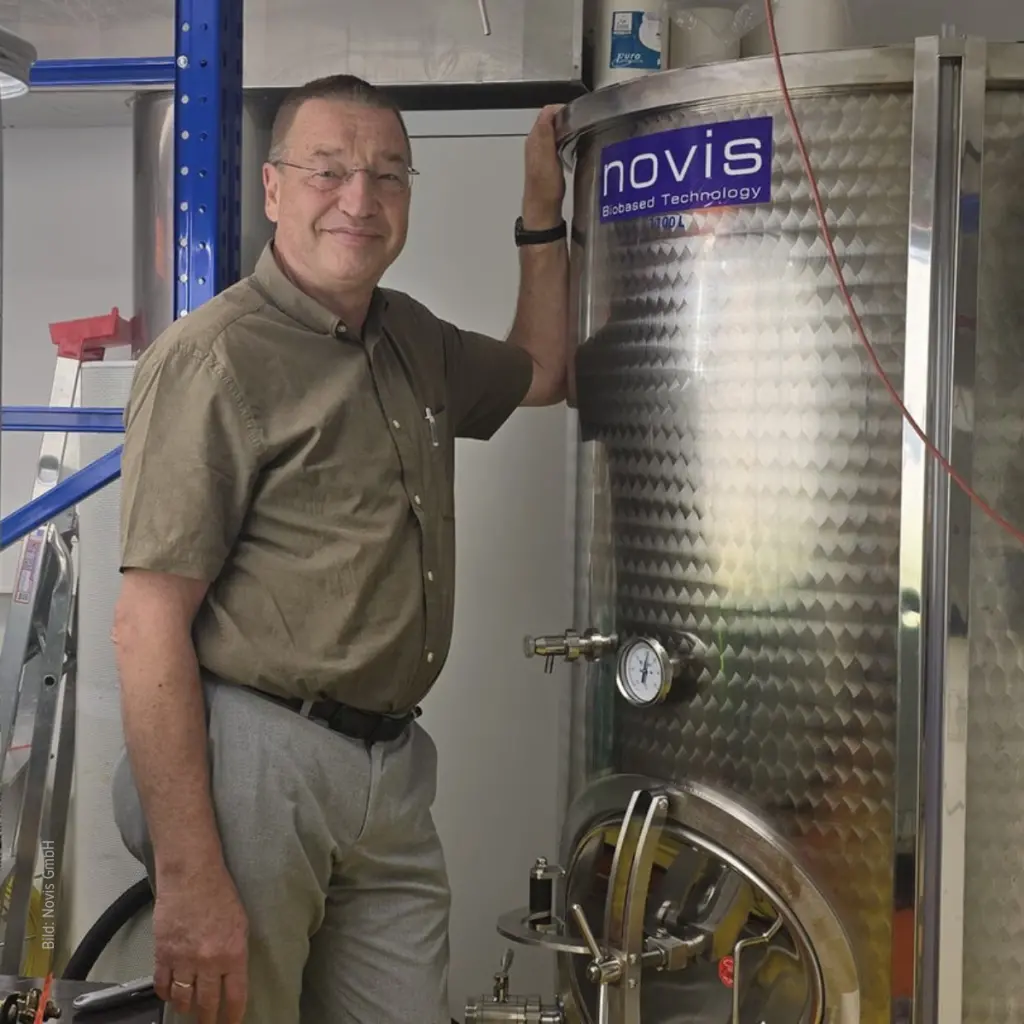 Der Geschäftsführer der Firma Novis steht vor einem großen Gerät, das aus Abgas CO2 Wertstoffe herstellt