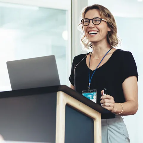 Businesswoman standing at  podium with laptop giving a speech. 